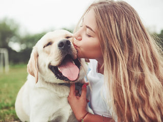 a woman kissing her labrador retriever